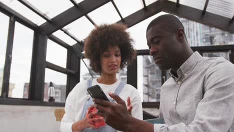 african man and mixed race woman using smartphone