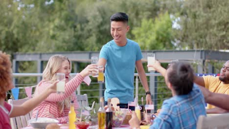 happy diverse group of friends making a toast at dinner table in garden, slow motion