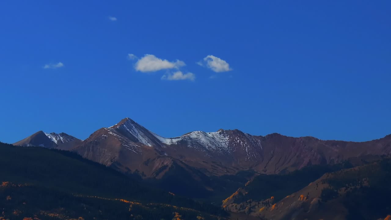 Opening shot Aspen Mount Snowmass Capitol Peak fall autumn sunny blue sky morning aerial drone Colorado White River National Forest valley snow dusting Rocky mountain peaks forward pan up pan down