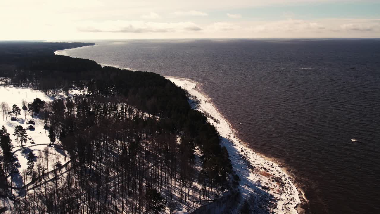 Droonilento meren yllä talvella. Jäätyneitä kiviä rannikolla