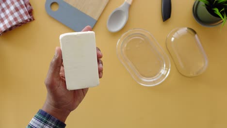 una persona sosteniendo un palo de mantequilla en una mesa amarilla