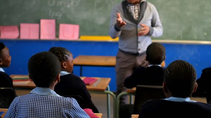 Male teacher teaching students in the class 4k