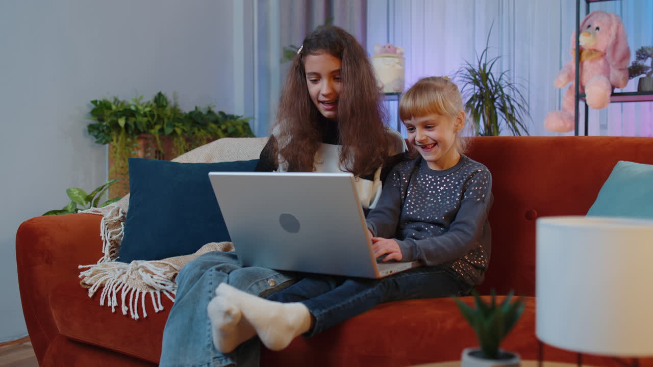 dos hermanas riendo mientras ven algo en una computadora portátil