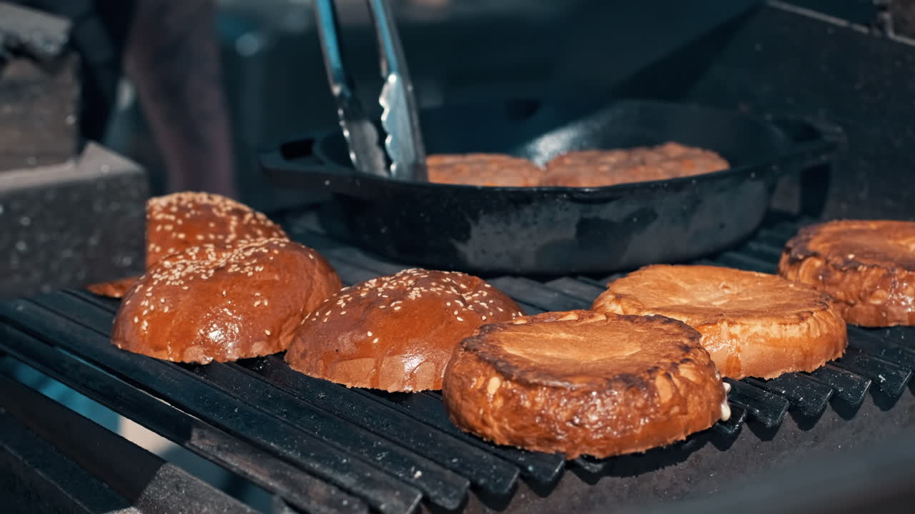 Frying patties and burger buns in a frying pan and grill. BBQ, slow motion