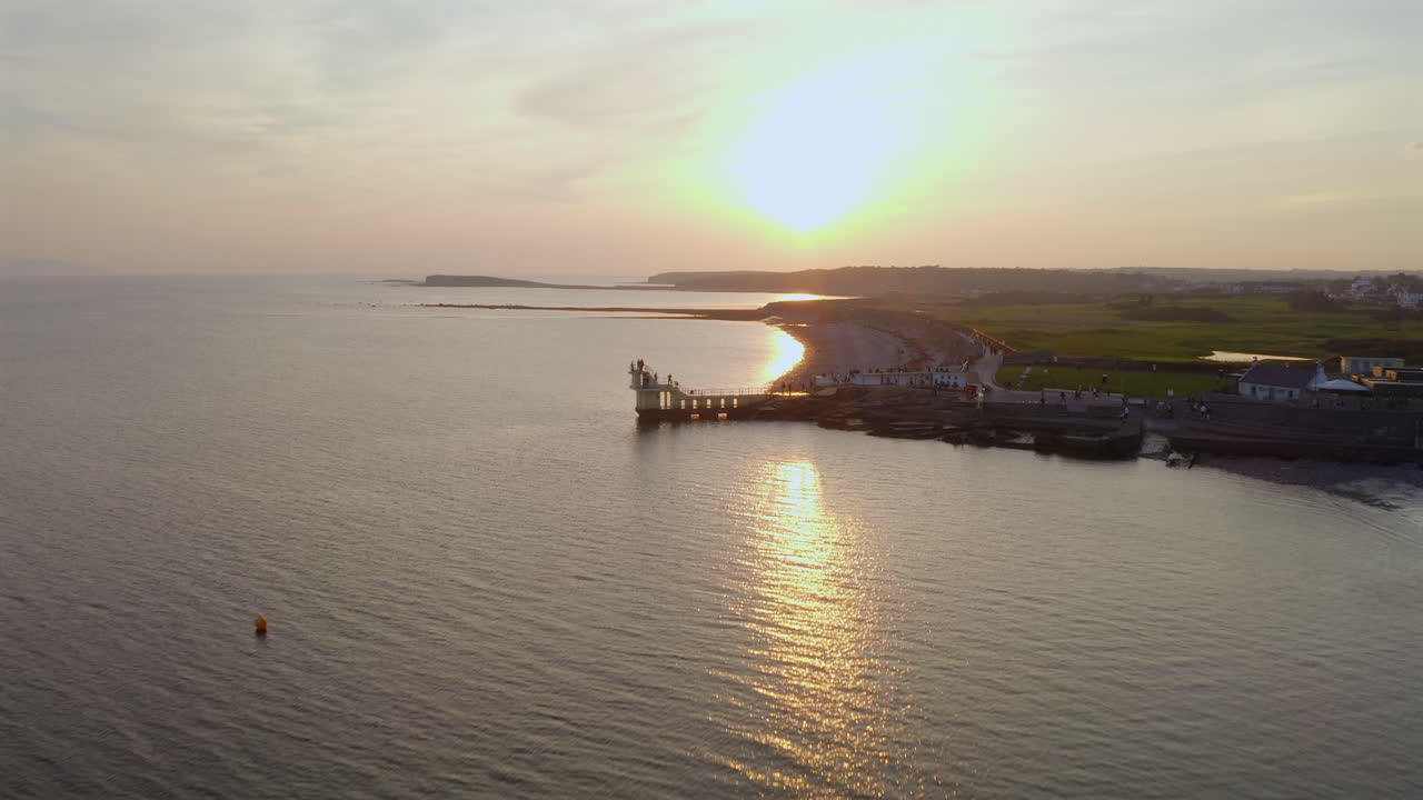Aerial approach as waves gently lap the shore near Salthill Blackrock Diving Board along the promenade in Galway Ireland