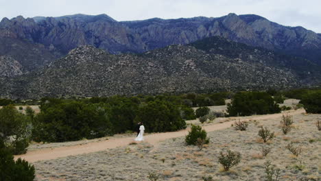 A couple walking on a desert path with majestic mountains in the background