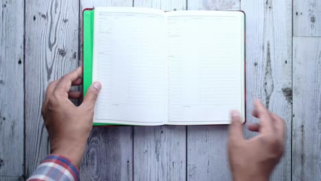 person opening a blank notepad on a wooden table