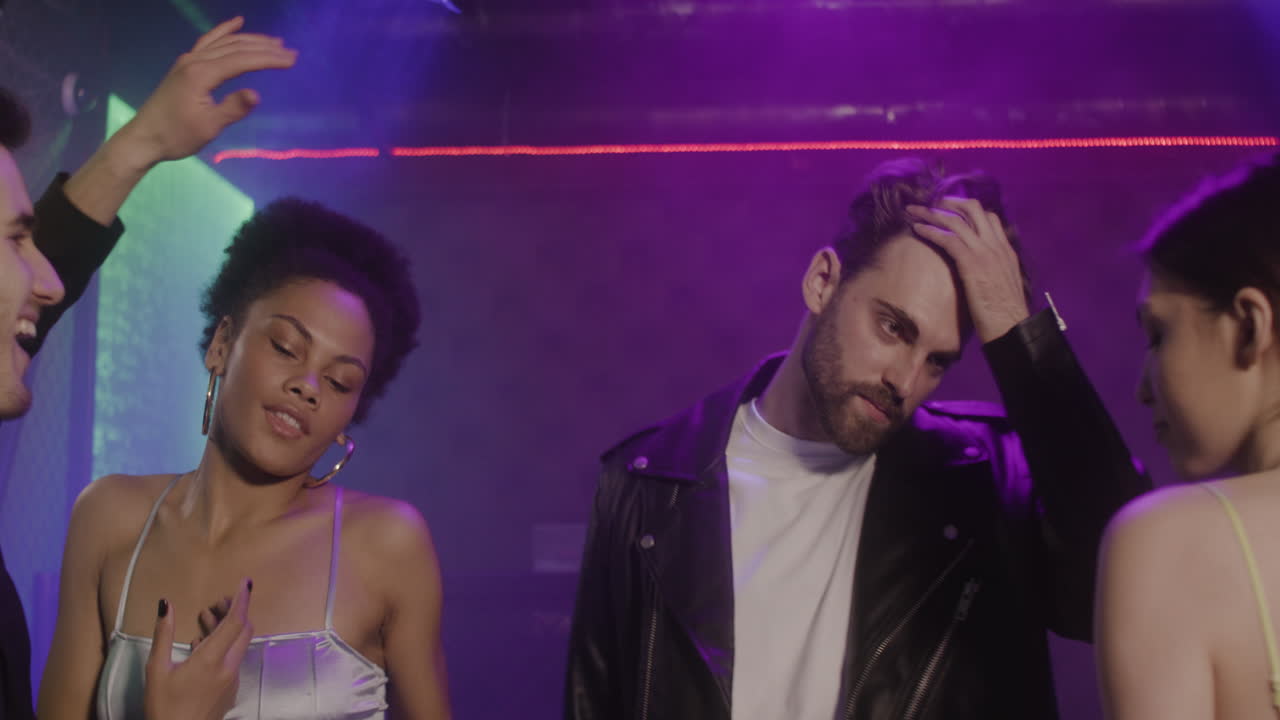 grupo de cuatro jóvenes amigos bailando en la discoteca