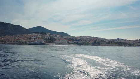 View-on-a-beautiful-city-Hvar-from-a-boat,-leaving-wave-trail-behind-it