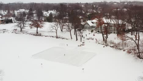 aerial, person skating with a hockey stick alone on small homemade outdoor ice rink