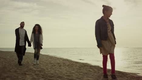 familia relajada disfrutando de la playa del atardecer. padres hijo caminando por la orilla del océano