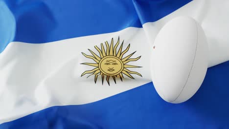 white rugby ball over flag of argentina with copy space, in slow motion