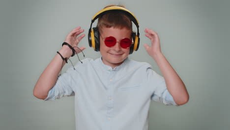 niño alegre escuchando música a través de auriculares y bailando discoteca divirtiéndose