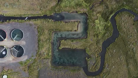 Top-down-aerial-of-river-flowing-away-from-purification-plant-in-Iceland