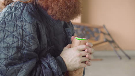 homeless man outdoors in jacket near broken bench extreme close up of beer can held in dirty hands