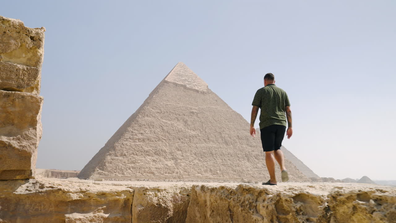 Man Sightseeing In The Famous Archaeological Site Of Giza Plateau In Giza, Egypt. Tracking Shot
