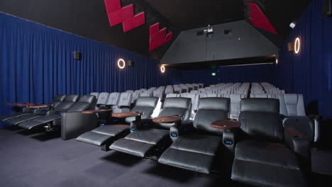 asientos reclinables de cuero de lujo en el cine con un proyector que emite destellos de luz, 4k