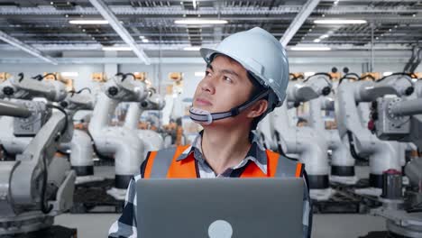 Engineer reviewing robotics operations on a laptop in a factory