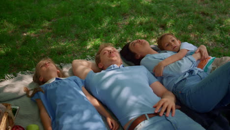 cheerful parents lying with kids on grass top view. happy family relax on nature