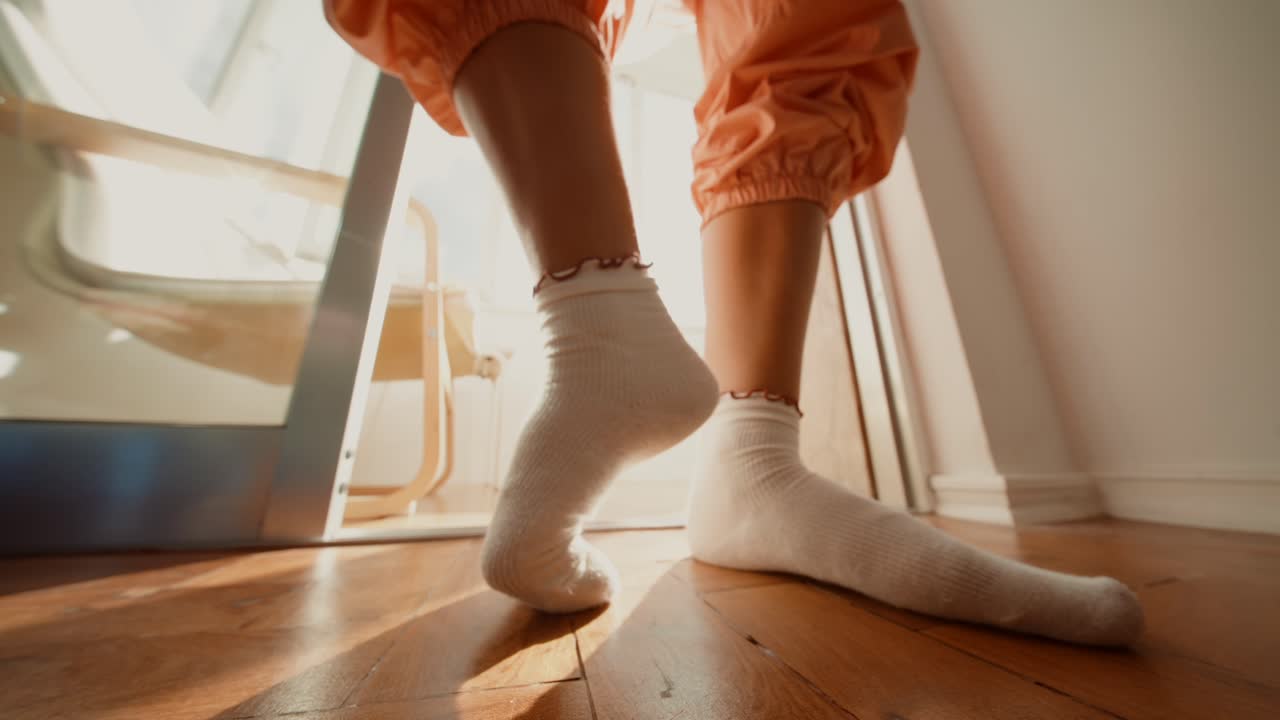 A person wearing socks and standing on a wooden floor