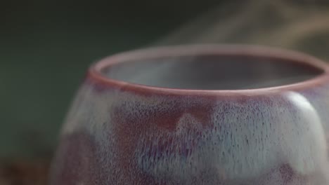 Macro-of-a-smoke-drifts-over-the-lilac-cup,-mug-with-yellow-light