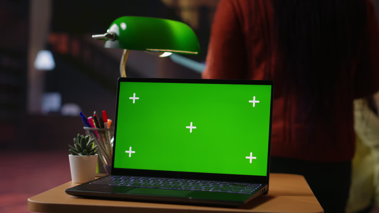 portátil con pantalla verde en una mesa por la noche