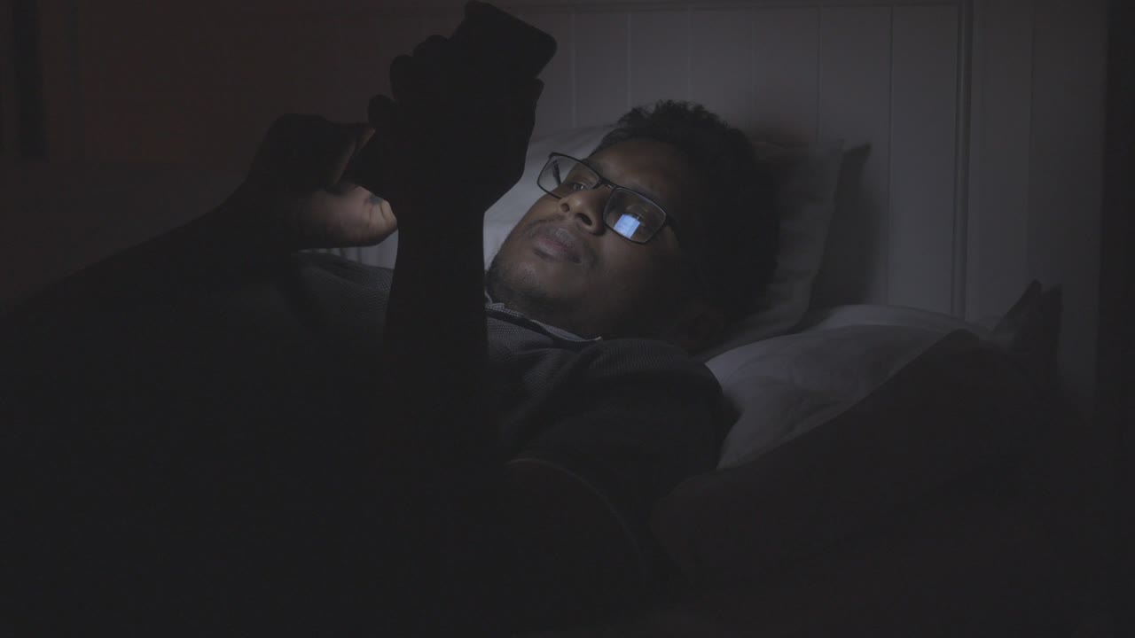 hombre usando teléfono inteligente en la cama por la noche
