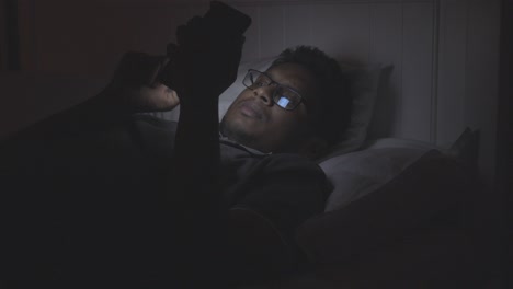 hombre usando teléfono inteligente en la cama por la noche