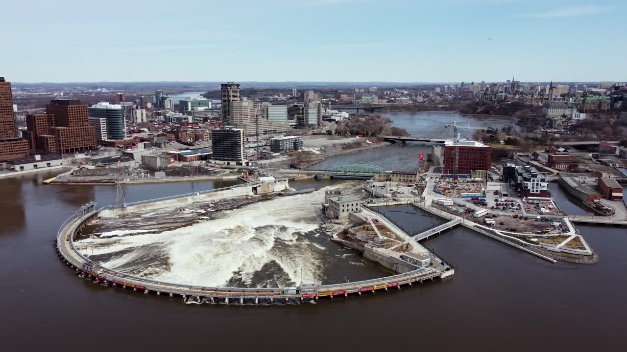 Drone orbiting around a hydro electric dam with downtown Ottawa and Gatineau in the distance