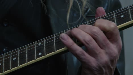 close-up of electric guitar ebony fretboard, man's fingers play music