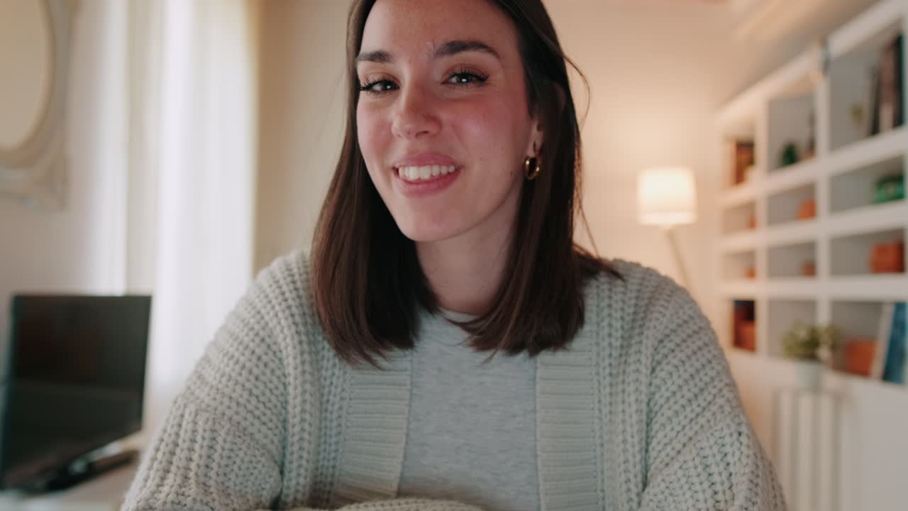 Mujer joven saludando y sonriendo durante una videollamada