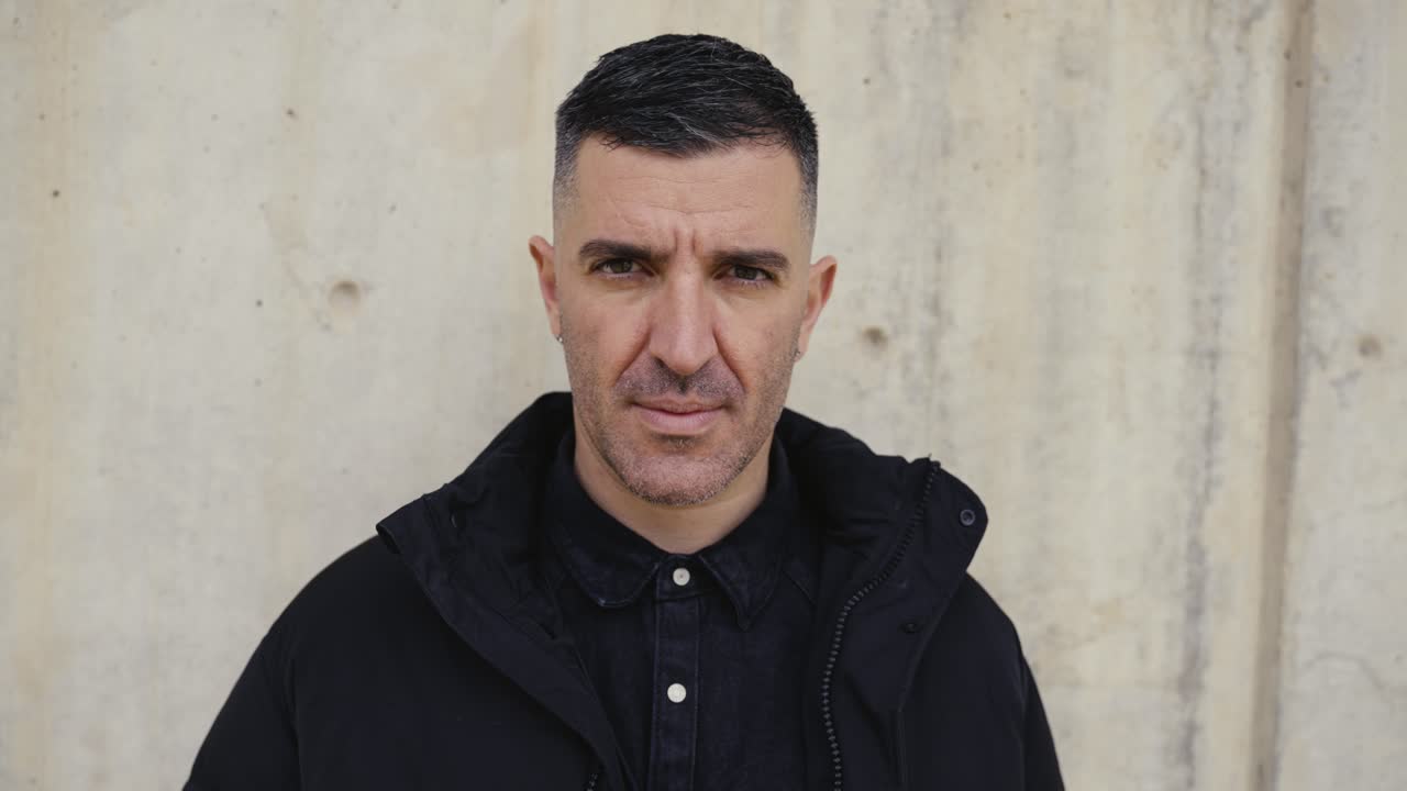 retrato del hombre mientras mira a la cámara con una expresión facial neutra y seria