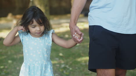 linda chica asiática sonriente caminando con su padre sosteniendo su mano