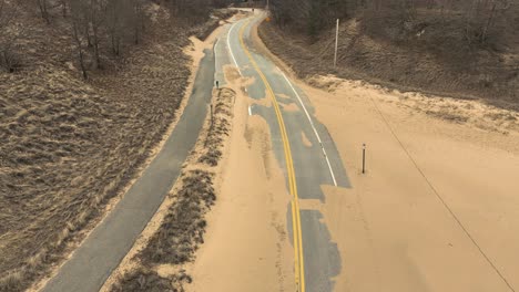 Aerial-at-high-angle-of-a-sand-covered-beach-street-in-Winter