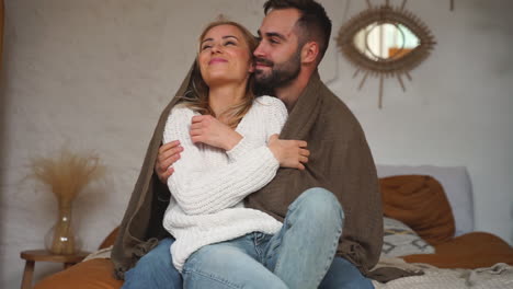 lovely man and woman wrap up warm with a blanket at home