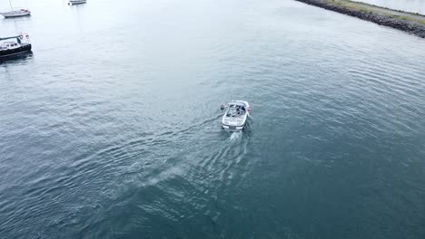 Following-speed-boat-aerial-view-navigating-quiet-river-Conwy-harbour-marina-seaside-town-slow-follow