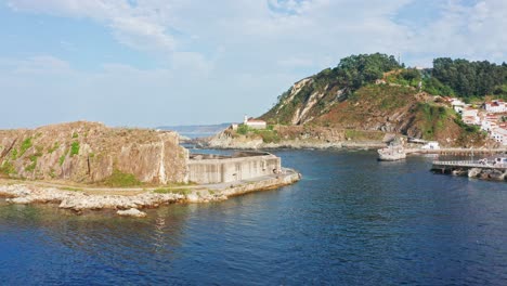 cudillero lighthouse on rocky cliff, flyover through port breakwater, asturias