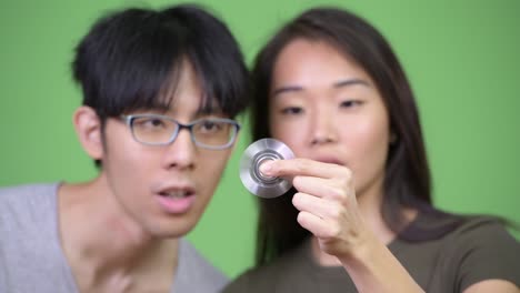 young asian couple playing with fidget spinner together