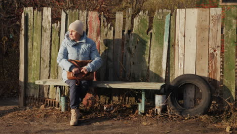 elderly woman sitting on a bench in a rural setting