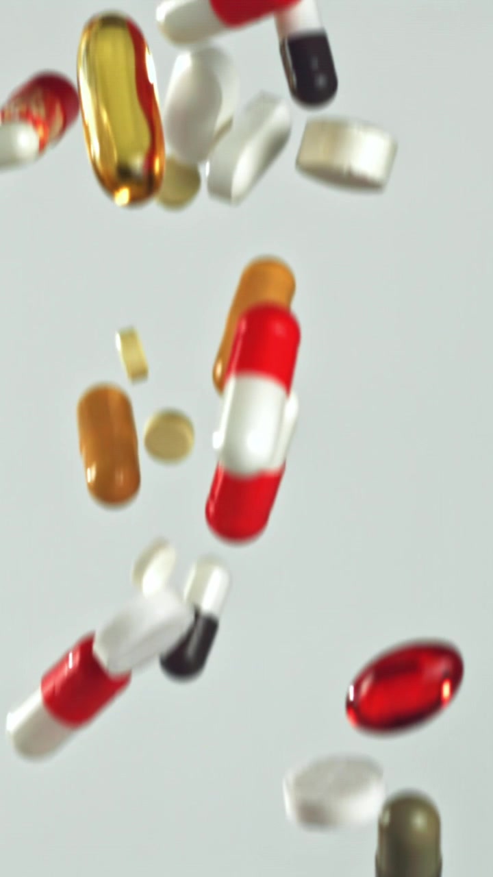 Varie pillole e capsule colorate che cadono al rallentatore