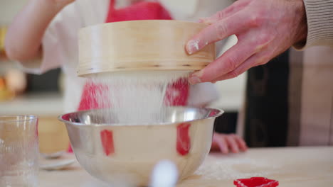 close up of sifting flour through a sieve while working in the kitchen