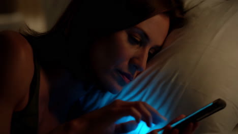 woman using a phone in bed at night