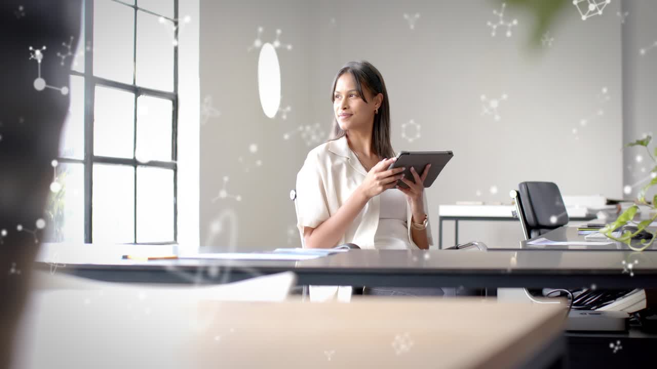 Woman tapping tablet at desk showing particle overlay reviewing business files and gazing outside