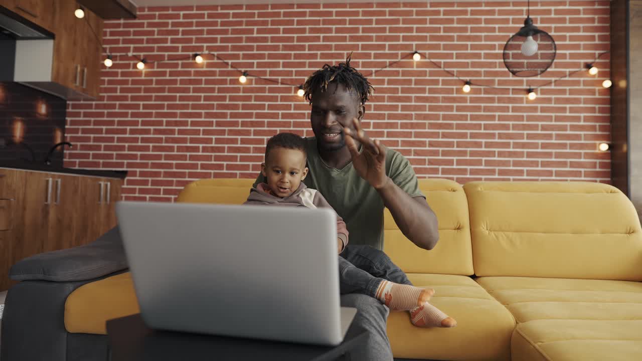 Portrait African American father and preschooler child speak on conversation video, greeting gesture