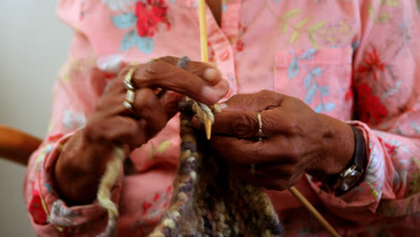 Mid-section-of-senior-woman-knitting-with-yarn-at-home-4k