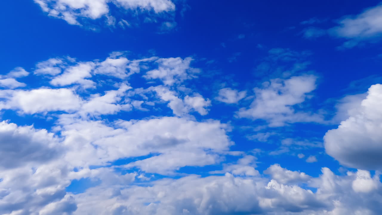 Thick cloudscape spreading by the atmosphere. White fluffy clouds appear in the azure sky. Low angle view. Timelapse.