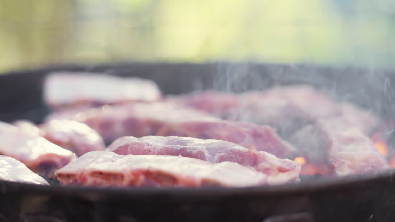 불타고 스모키한 바비큐 그릴에서 굽는 고기를 슬로우 모션으로 밀어 넣습니다.