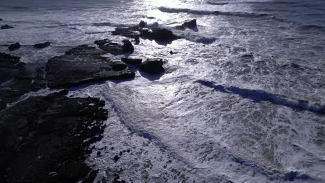 Drone-fly-over-crashing-waves-and-rock-formations-at-Mavericks-Beach,-California-during-sunset