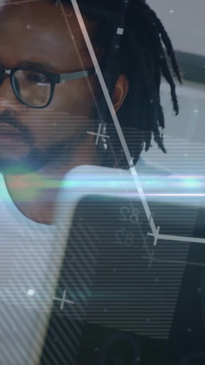 Vertical video: Man leaning into laptop working as camera tilting and tech covering face, screen