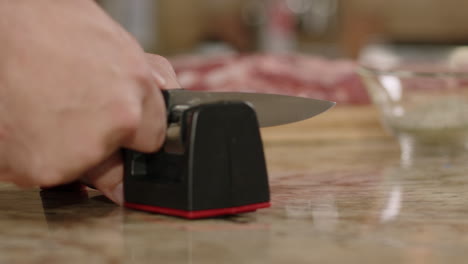 rack focus from raw bbq pork ribs to man sharpening knife in slow motion